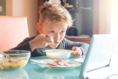 Blond boy eating breakfast and watching the table