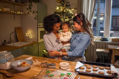 Two women holding a baby in a kitchen